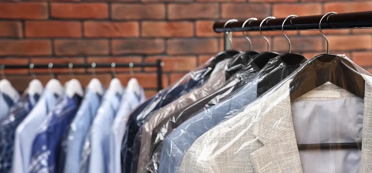 Dry-cleaned shirts and a jacket in protective covers on a garment rail