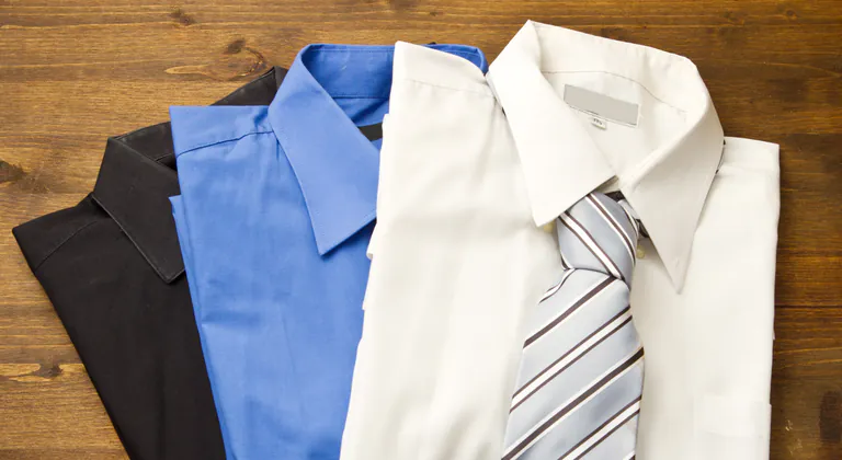 Freshly pressed dress shirts folded with a tie