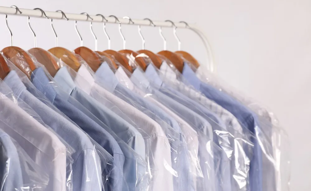 Freshly dry-cleaned shirts in protective covers on wooden hangers