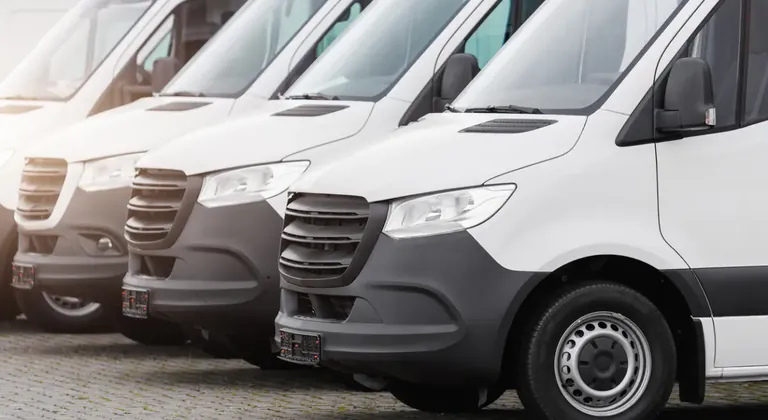 Row of white pickup and delivery vans parked side by side